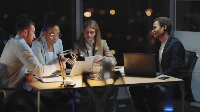 International young team of corporate leaders gather in boardroom night office to discuss collaboration agreement. Coworkers group. Business people.