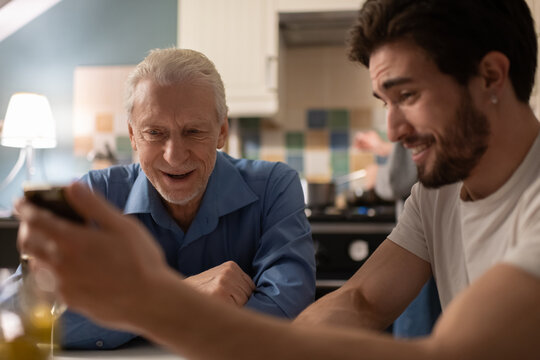 Young man showing funny photos to father