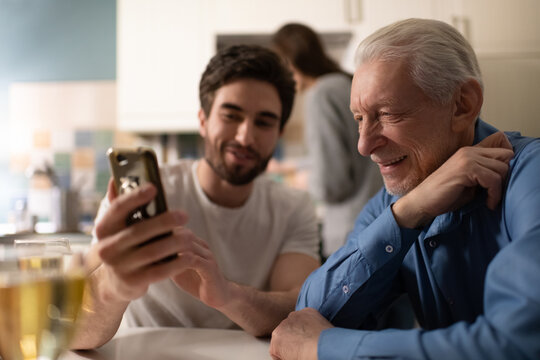 Senior man watching photos on smartphone of son