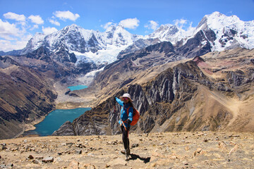 Fototapeta premium Happy trekker enjoying the view of Laguna Jahuacocha and the entire Cordillera Huayhuash, Ancash, Peru.