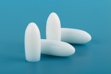 Medical suppository on a blue background.White rectal and vaginal unpacked candles.Soft focus.Сoncept of treatment of female diseases,hemorrhoids,cracks,anti-inflammatory,from temperature.