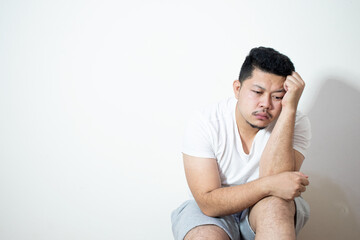 Portrait of unhappy and depressed man with black hair, feeling ashamed or sick, keeping eyes closed. Human face expressions and emotions concept. Isolated studio shot on gray background.