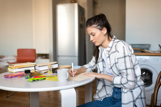 Teenage girl thoughtfully writing notes for exam