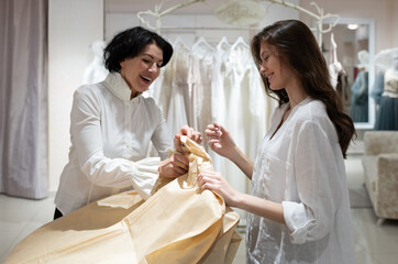 Cheerful shop owner packing dress and talking to satisfied female client