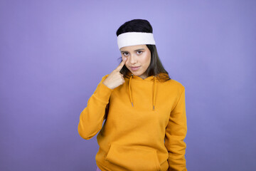 Young latin woman wearing sportswear over purple background Pointing to the eye watching you gesture, suspicious expression