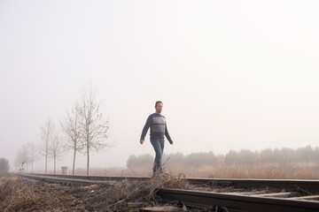 Man in dense fog are walking along the railway tracks.