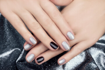 Silver manicure. Women's hands with beautiful manicure on a silvery shiny background.