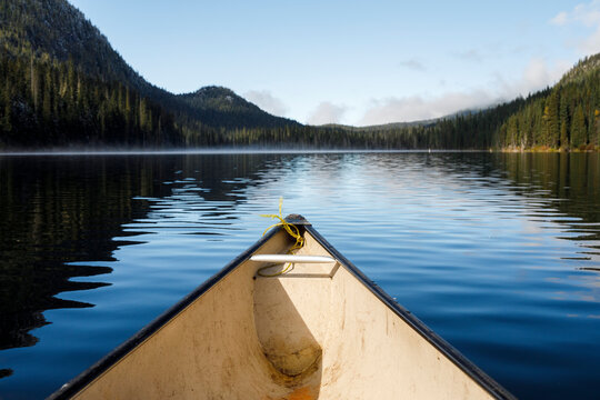 Bow of canoe on tranquil lake in Canada surrounded by forest