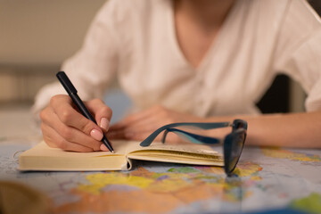 Anonymous female writing trip route in notepad