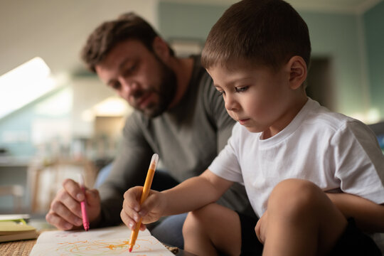 Focused boy drawing with father