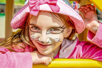 portret of girl in pink clothes with a kitten face painting