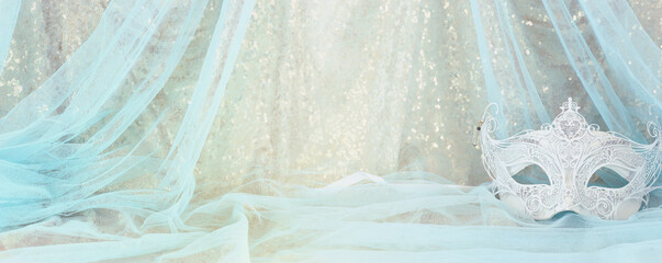 Photo of elegant and delicate Venetian mask over gold and blue chiffon background