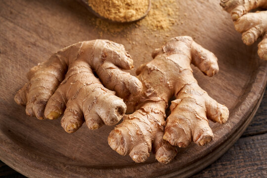 Fresh ginger root, with ginger powder in the background