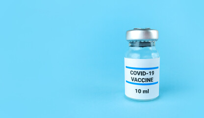 Medicine bottle with covid 19 vaccine on blue background with copy space.