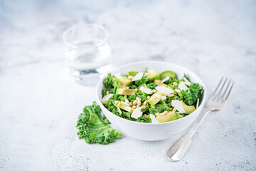 Kale avocado pine nuts cheese salad with lemon dressing in a bowl