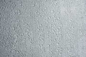 Closeup of rain drops on window on grey sky background