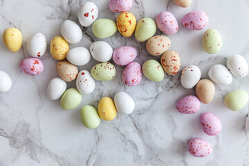 Happy Easter concept. Preparation for holiday. Easter pastel candy chocolate eggs sweets on trendy gray marble background. Simple minimalism flat lay top view copy space.