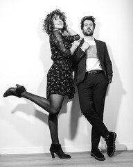 A caucasian couple in a black and white fashion shoot on valentine's day leaning against the wall