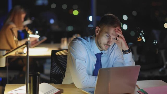 Worried young business manager working long hours at office feeling very overwhelmed. Concept for stressful job, deadline and exhaustion.