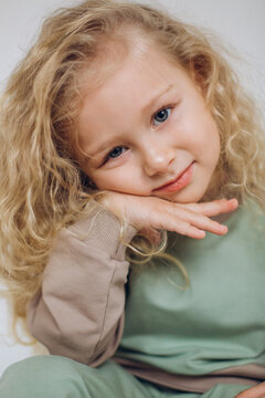 Cheerful adorable curly blondie girl on isolated background. Stylish expressive emotional kid portrait