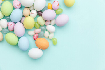Happy Easter concept. Preparation for holiday. Easter candy chocolate eggs and jellybean sweets isolated on trendy pastel blue background. Simple minimalism flat lay top view copy space.