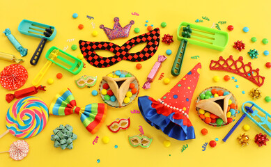 Purim celebration concept (jewish carnival holiday) over yellow background. Top view, flat lay