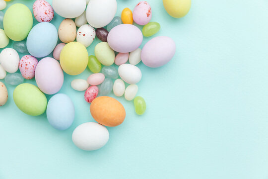 Happy Easter concept. Preparation for holiday. Easter candy chocolate eggs and jellybean sweets isolated on trendy pastel blue background. Simple minimalism flat lay top view copy space. © Юлия Завалишина