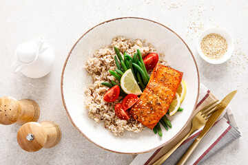 Salmon fish fillet baked, rice, green beans and tomatoes in lunch bowl. Healthy food, top view