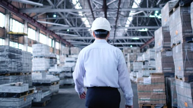 Follow footage of employees male warehouse worker engineer in hard hat working. walking through logistics center warehouse factory construction site logistics architect businessman man builder indoors