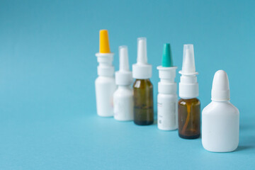 Bottles of nasal spray standing in line on blue background, medicine flat lay, treatment for colds