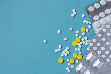 White and yellow pills flat lay for blogger medicine content with copy space on blue background