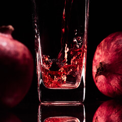 Glass in the low-key lighting with two pomegranates and juice