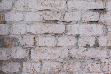 Textural detail of the old brick wall of the house, under white paint. Close-up