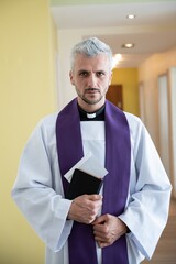 Catholic priest holding envelope with money during pastoral visit. Church and money.