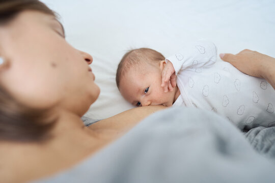 Beautiful woman breastfeeding her baby in a cozy house on the bed. High quality photo