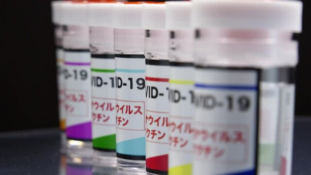 CORONAVIRUS (COVID-19) VACCINE in laboratory. Colorful glass bottle of liquid remedy for injection use. Manufacture drugs for medical supplies of pharmacy industry. Label written in Japanese word.
