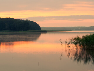 Fototapeta na wymiar Sunrise reflection landscape. Orange sky and water. Seksty lake, Masuria in Poland.