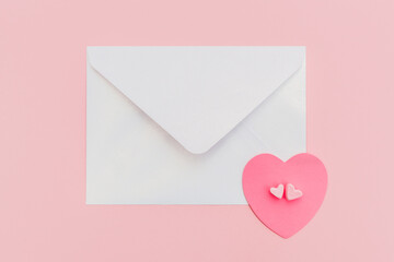closed pearlescente envelope with paper heart on the pink background