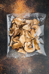 Dried porcini mushrooms, on old dark rustic background, in plastic pack, top view flat lay