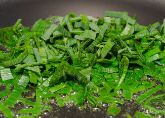 Fresh healthy organic green vegetable garlic chopped in a frying pan 