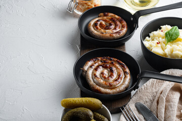 Rustic food with roasted sausage mashed potatoes and sour cabbage in cast iron frying pan, on white background , with space for text  copyspace