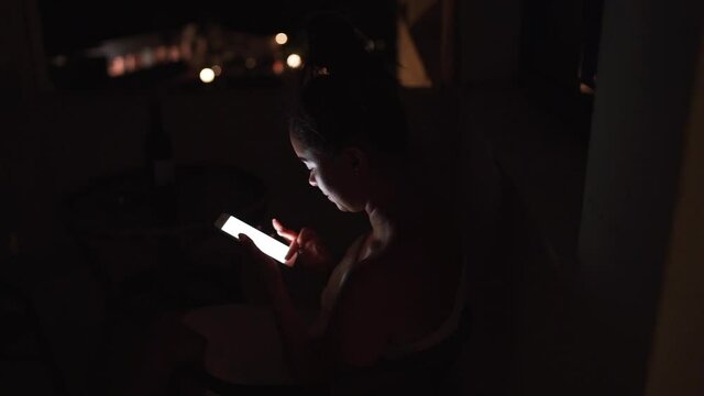 Girl scrolls her timeline in the phone in the night. Young lady surfs the Internet in the night. High quality FullHD footage