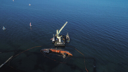 sunken ship top view. shooting by a quadcopter. overhead crane is trying to lift the ship. water accident