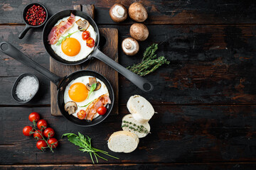 Fried eggs with cherry tomatoe and bread for breakfast in cast iron frying pan, on old dark  wooden table background, top view flat lay , with space for text  copyspace