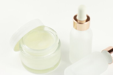 Glass cosmetic container with face body cream and transparent bottles with pipette, skin care treatment laboratory, cosmetics medicine jar on white background