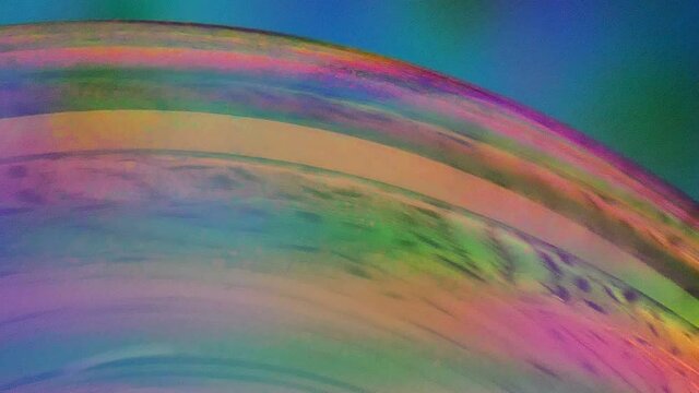 Close up of colorful, swirling soap bubble. Blue background.