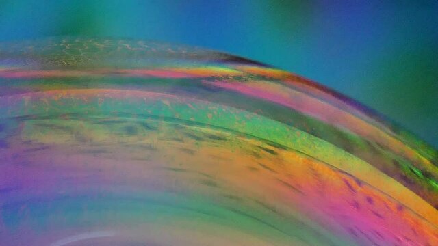 Swirling colorful soap bubble close up on blue background