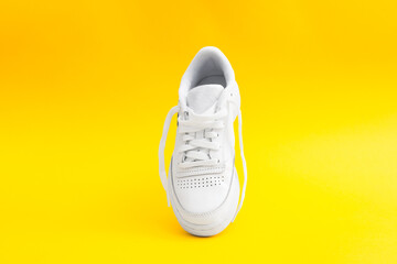 One women's stylish white casual sneaker on yellow background