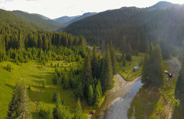 Aerial drone panorama of a mountainous meadow and a stream flowing through it. Perfect camping place for hikers or for nature lovers. Lotru Massif, Carpathia, Romania.