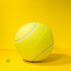 Pelota de tennis concepto grande chico sobre fondo amarillo